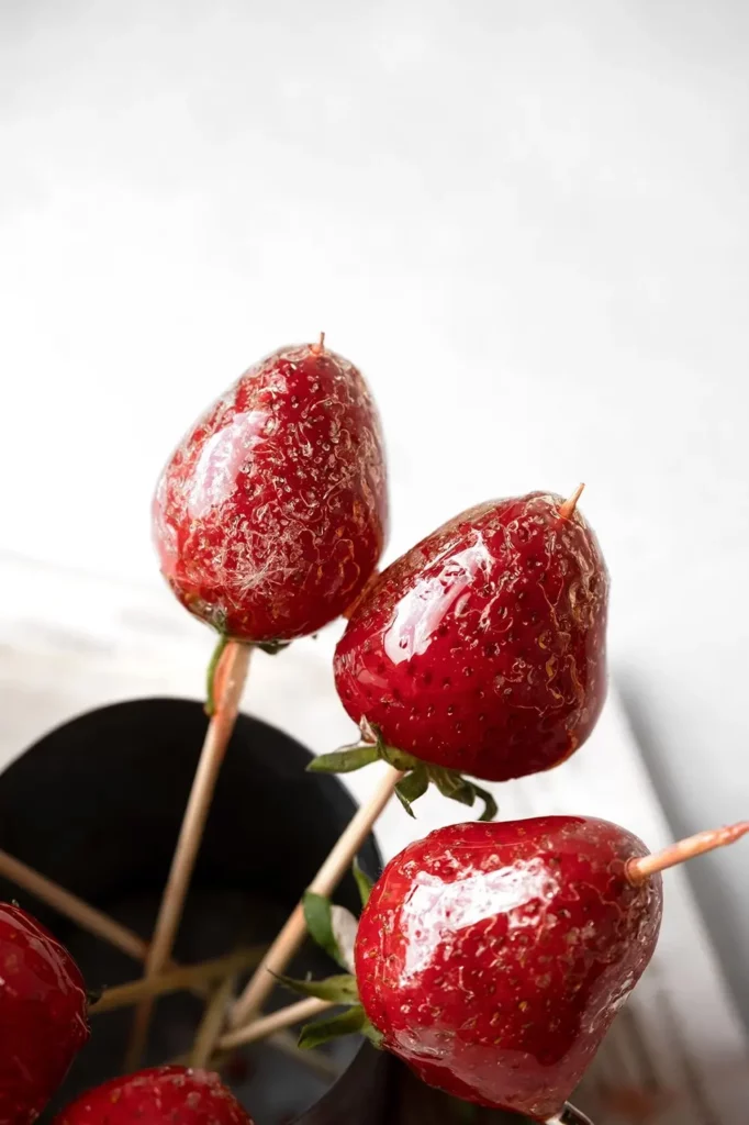 Fraises enrobées de sucre croquant sur des brochettes